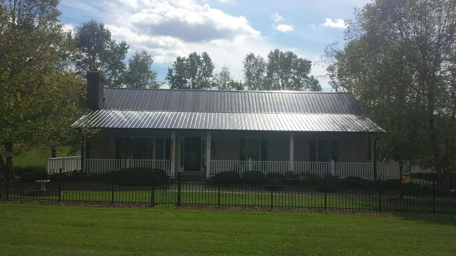 Gray metal roof on a brick ranch with a full width front porch — Gutter Guard Installation work by our crew in Alviso