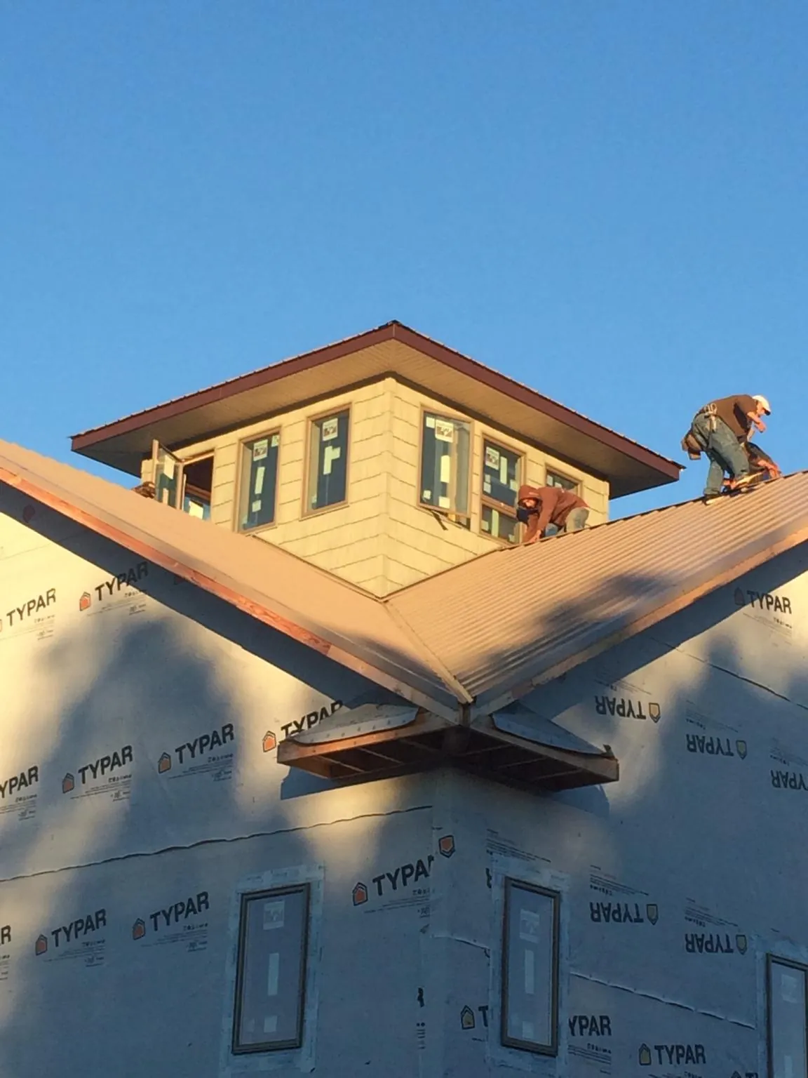 Roofers working around a rooftop cupola on a new metal roof at sunset — Roof Waterproofing in Alviso by Roofing Brothers